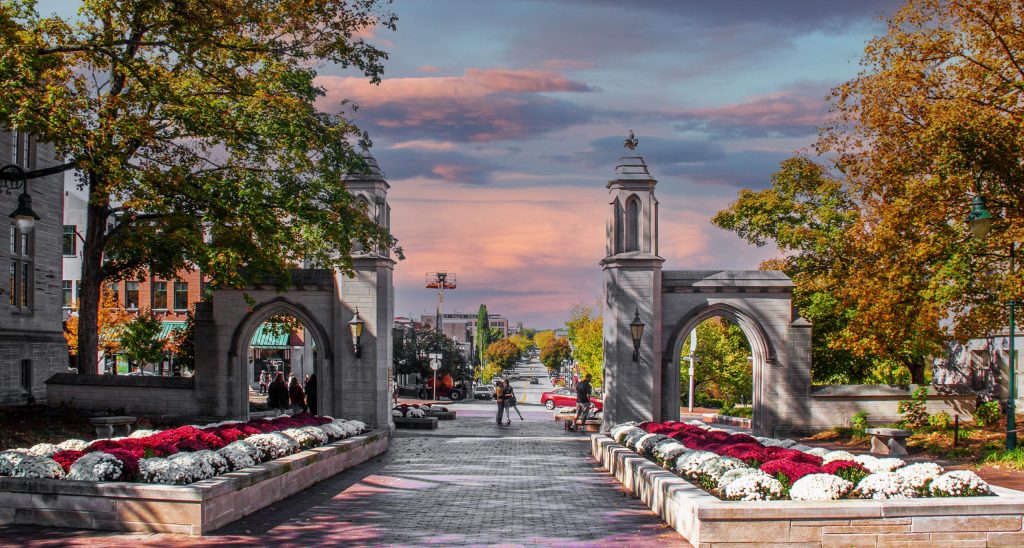 Overlooking Bloomington Indiana from University entrance on fall day at sunset with flowers and a view of the main street and unidentifiable people