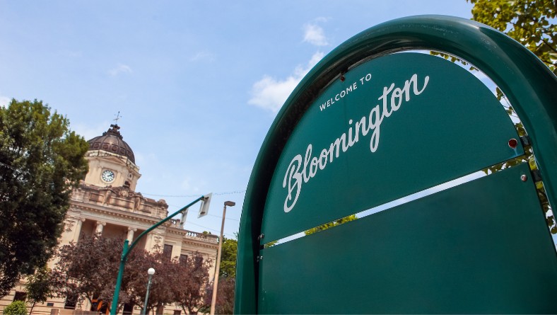 Welcome to Bloomington Indiana sign with downtown courthouse in the background