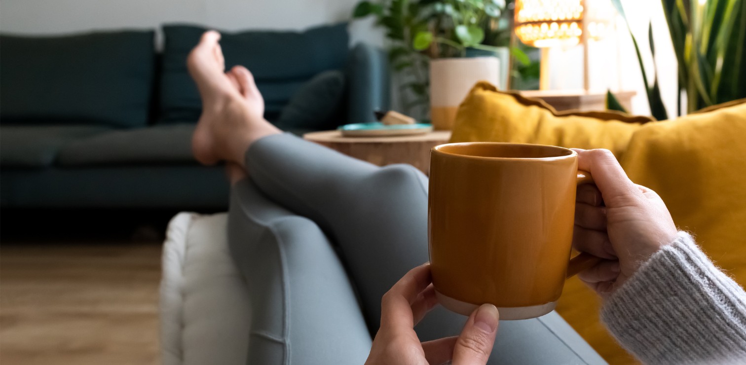 person relaxing on a couch with a cup of coffee