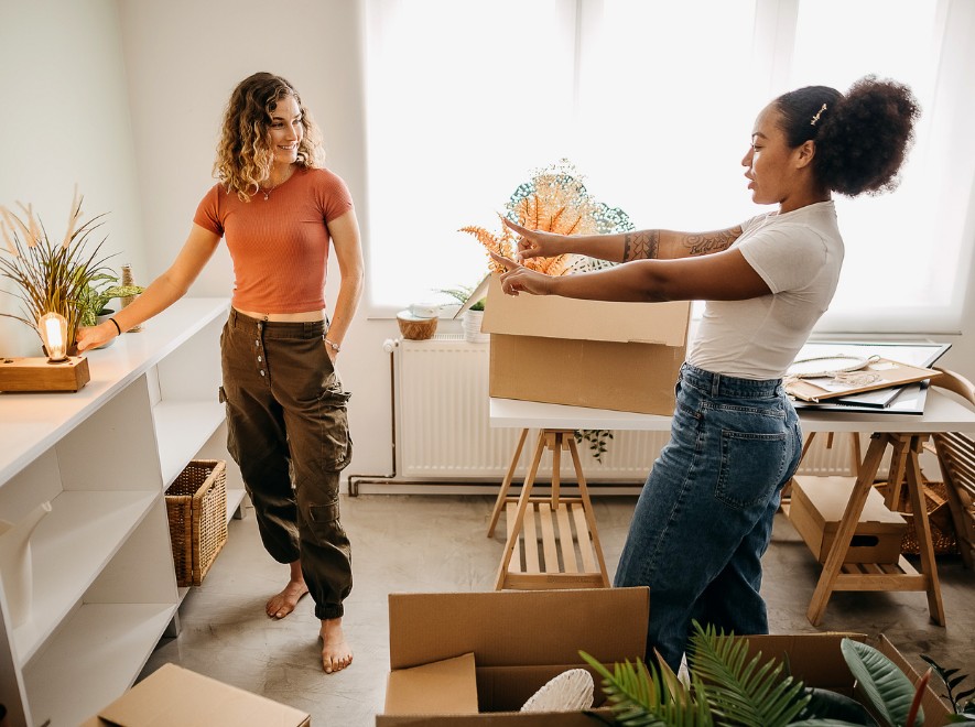 two young females arranging a room that they are in the process of moving into
