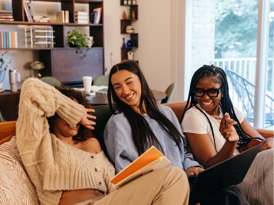 a group of young females smiling while studying on a couch.